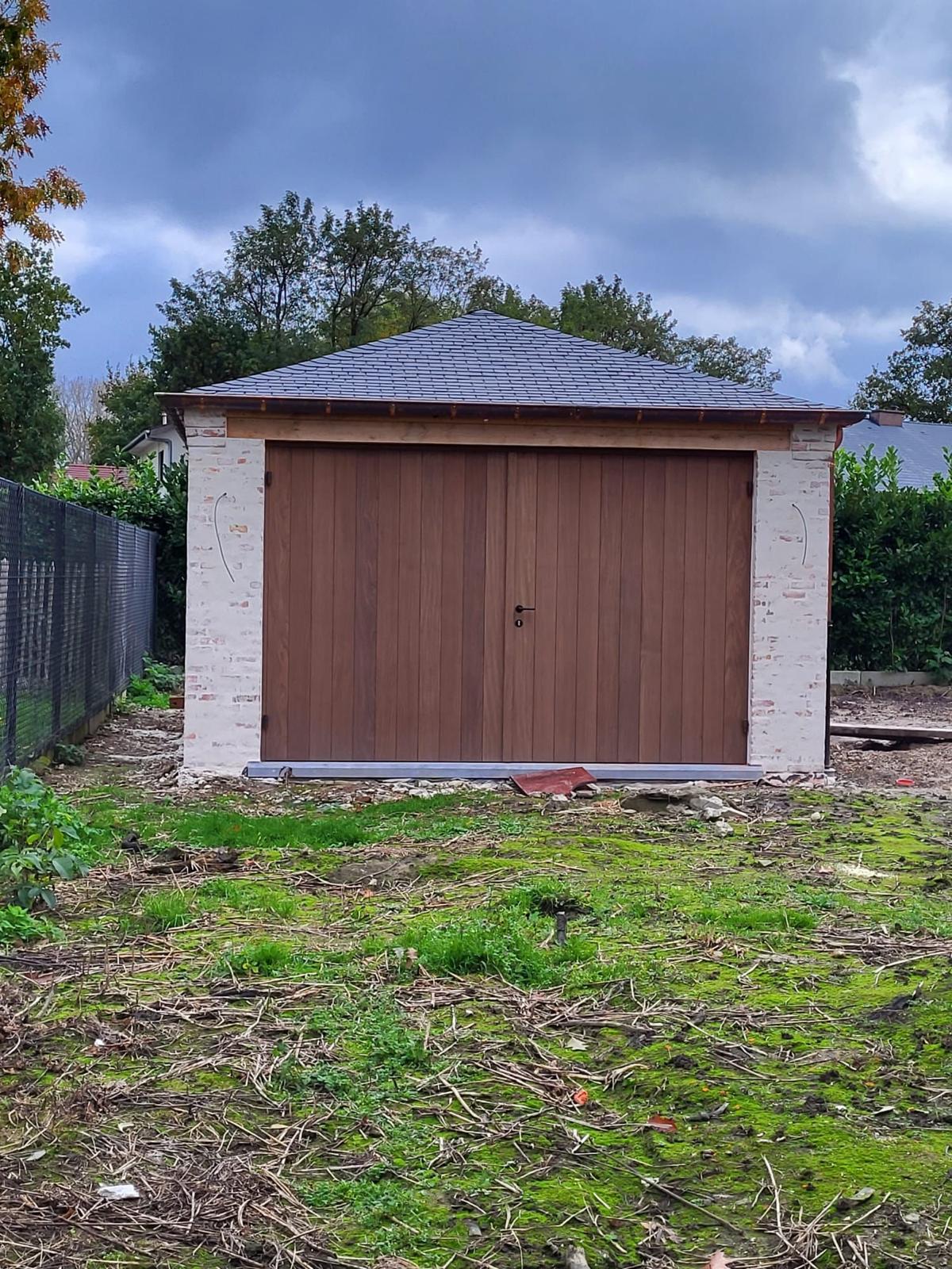 Vrijstaande garage in gekaleid metselwerk met houten poort en leien dak