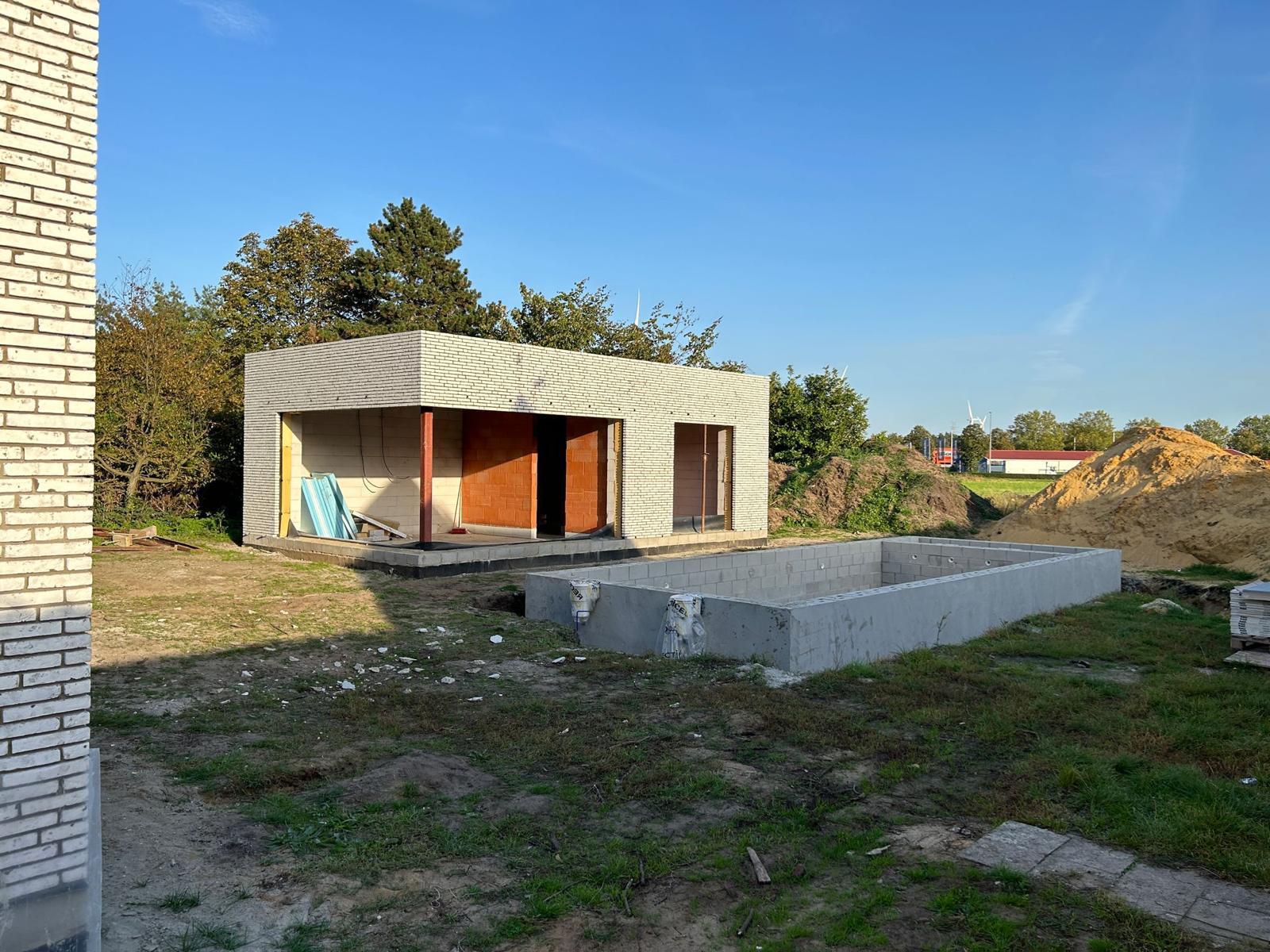 Poolhouse in lichte baksteen met betonnen zwembadconstructie in aanbouw