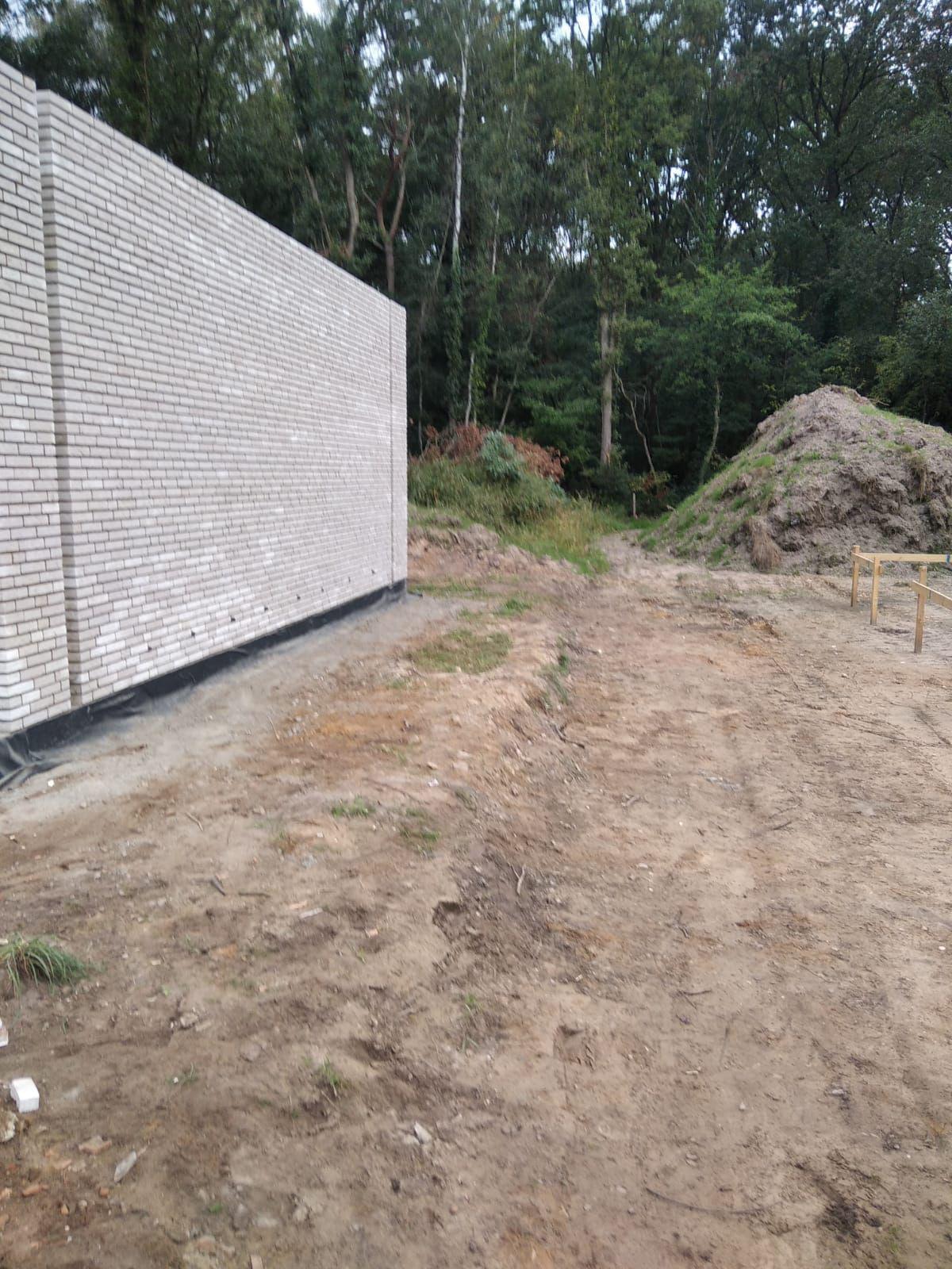 Gemetste tuinmuur in lichte baksteen langs bouwterrein in Limburg