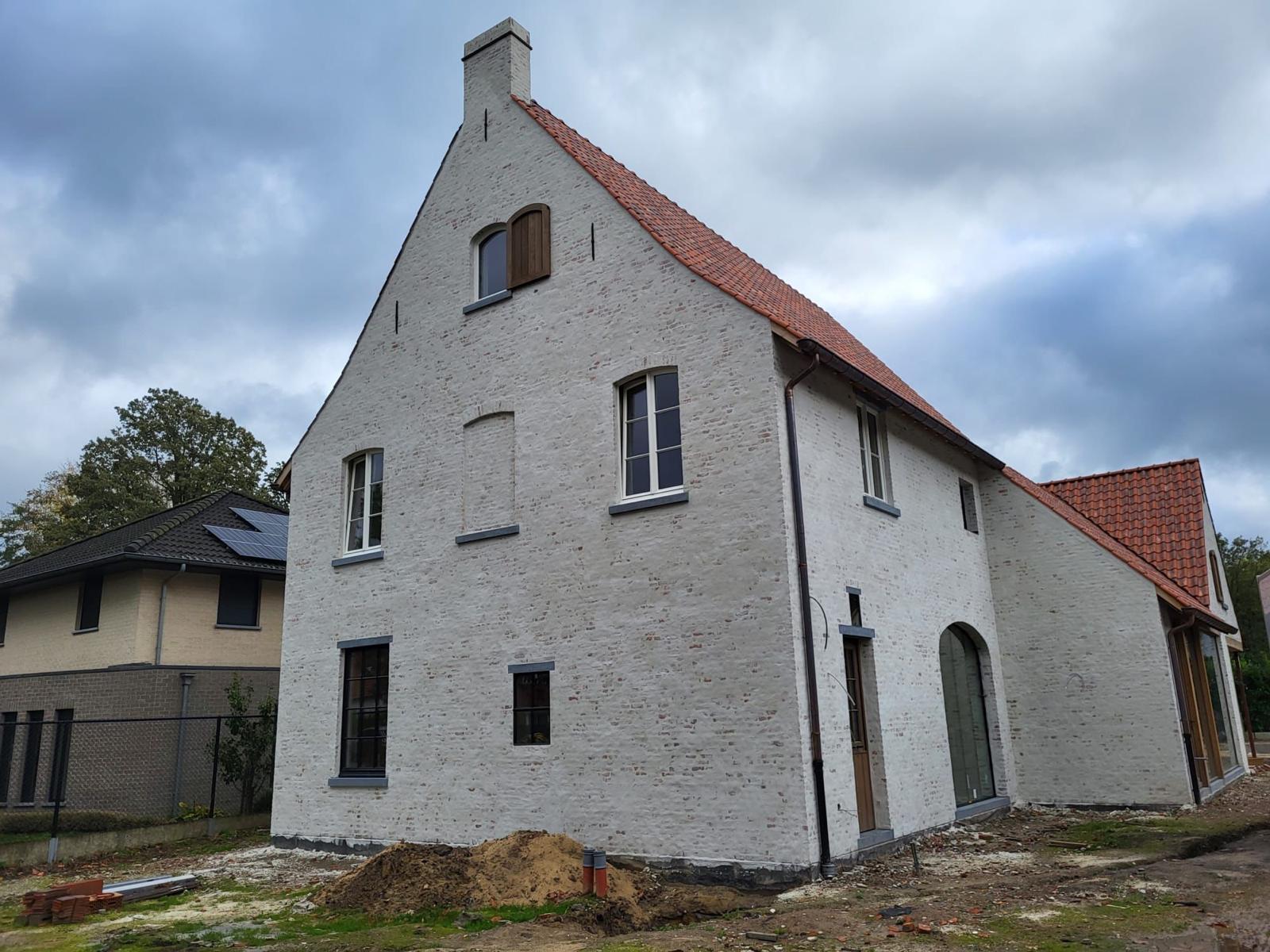 Landelijke nieuwbouwwoning met witgekaleide gevel en rode dakpannen
