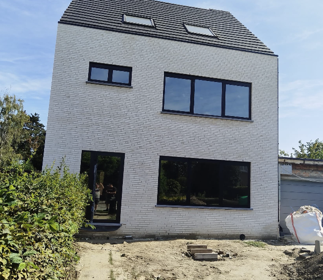 Nieuwbouw woning in witte baksteen met zwart schrijnwerk — ruwbouw door IMW Building