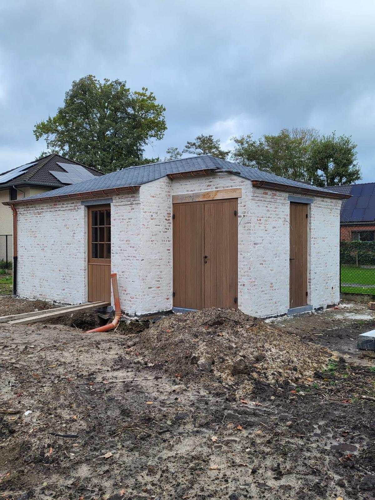 Bijgebouw met gekaleide baksteen, koperen goten en houten poorten