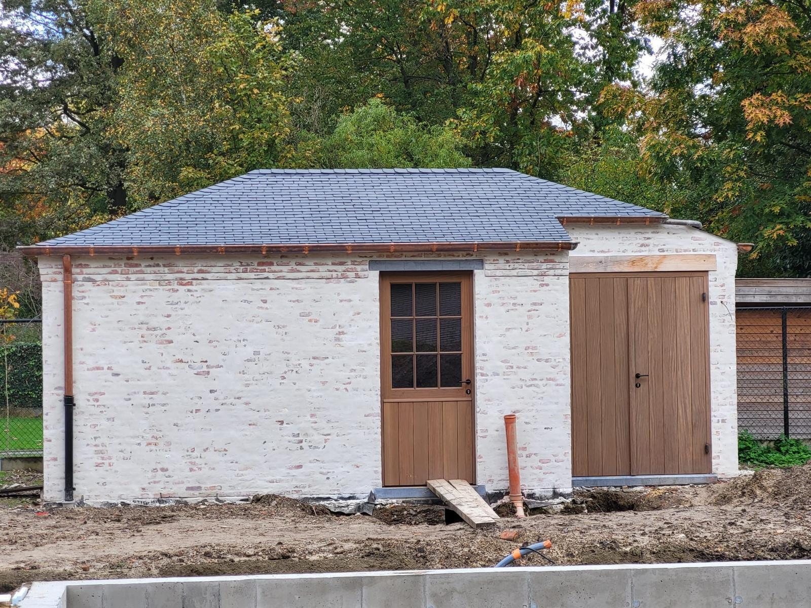 Afgewerkt tuinhuis met leien dak, koperen goten en houten deuren