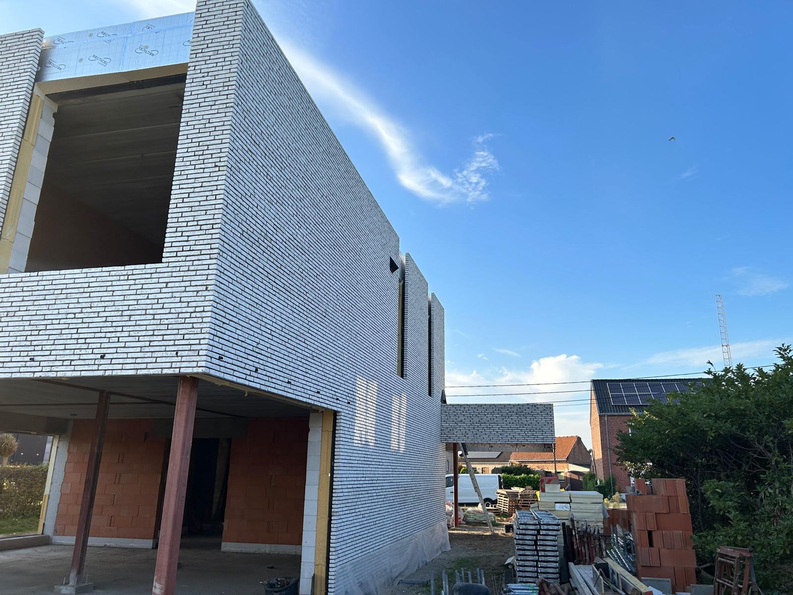 Detail van gemetselde witte baksteengevel met betonnen welfsels en snelbouwsteen binnenmuren