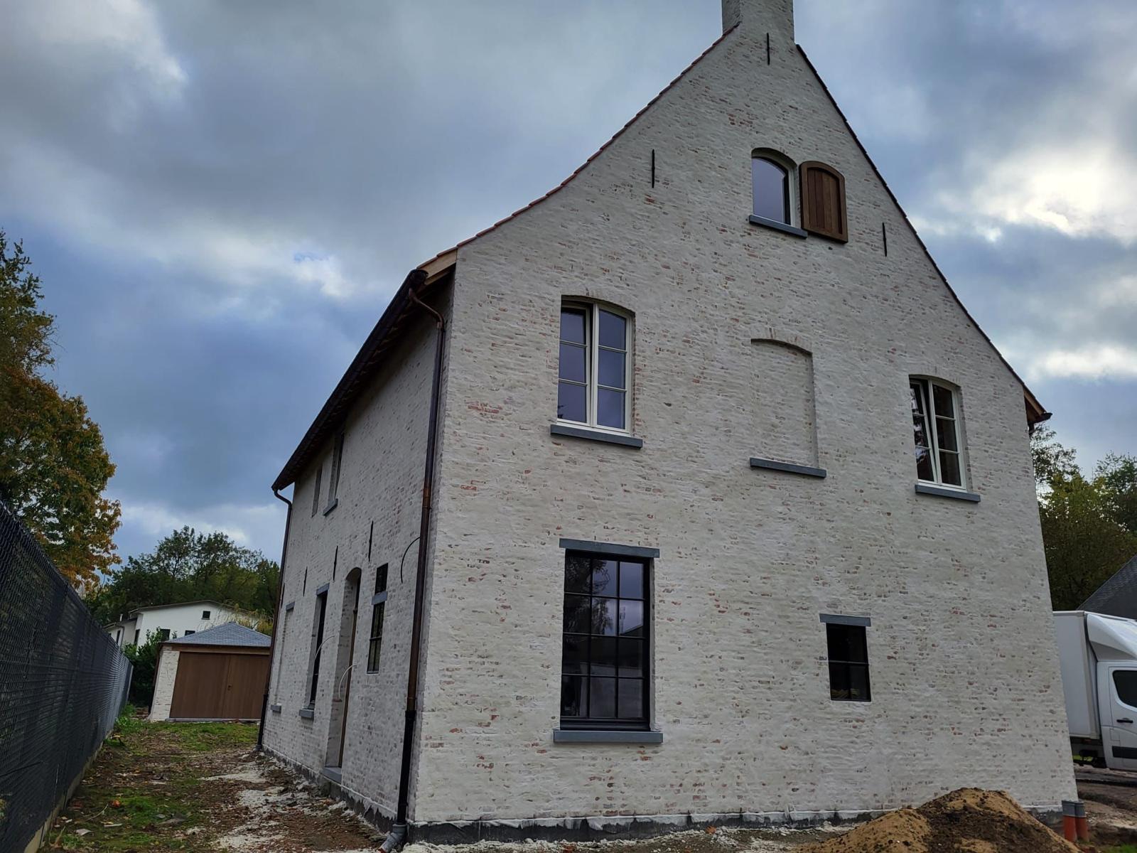 Gekaleide baksteengevel met puntgevel, schouw en zwart schrijnwerk na nieuwbouw door IMW Building