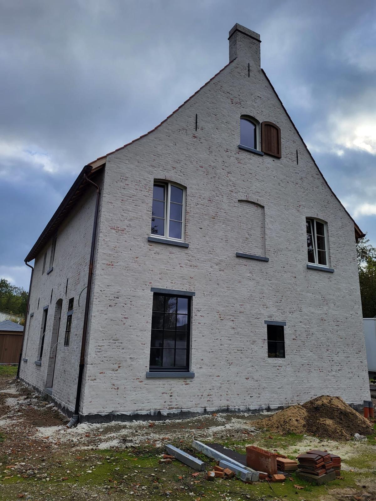 Puntgevel in witgekaleid metselwerk met boogramen en natuurstenen dorpels
