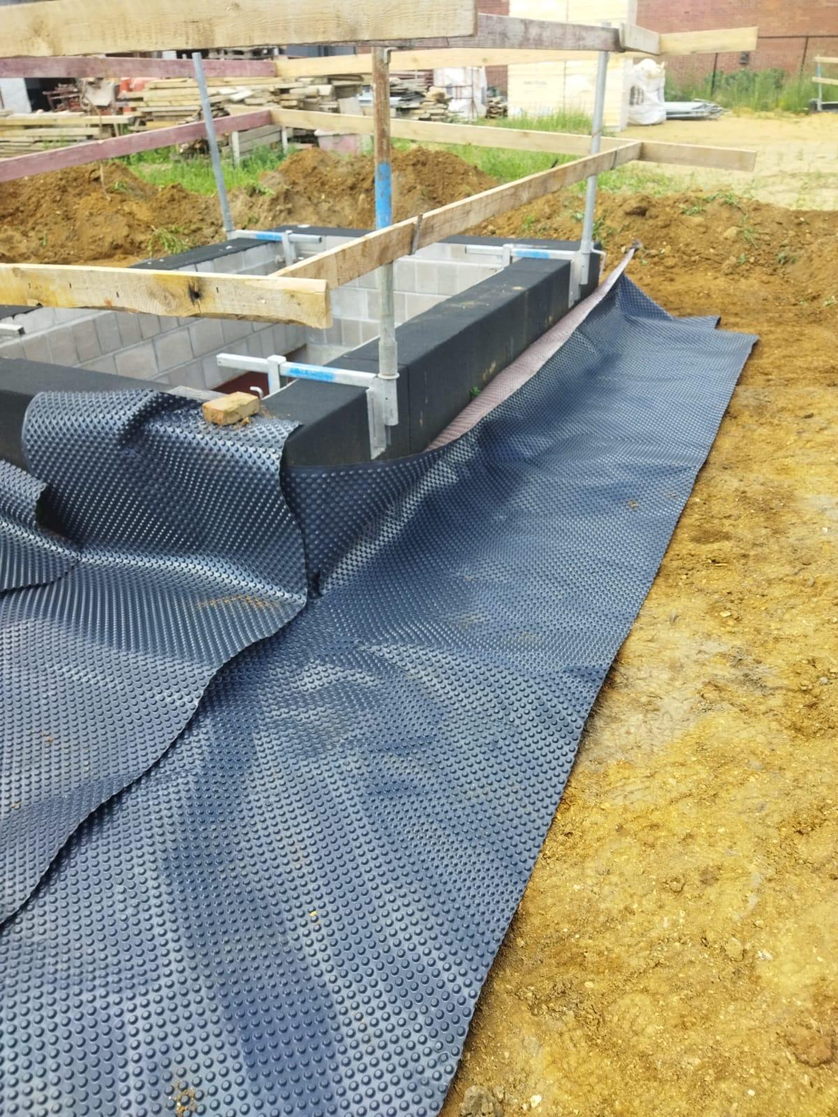 Detail waterdichting fundering met noppenfolie en betonblokken met bekisting — ruwbouw door IMW Building