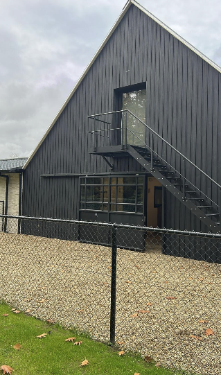 Detail zwarte houten gevel en stalen trap van nieuwbouwvolume
