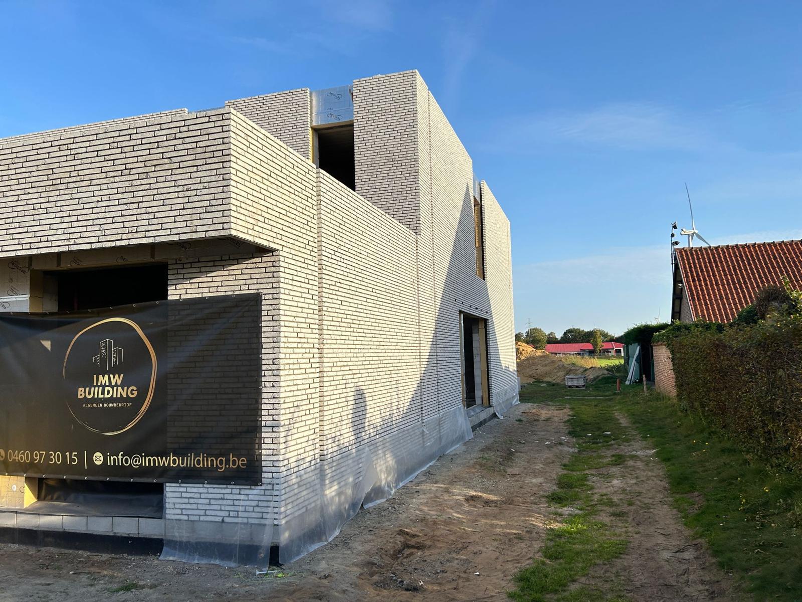 Zijgevel van nieuwbouwwoning in lichte baksteen met vooruitstekende volumes — ruwbouw door IMW Building