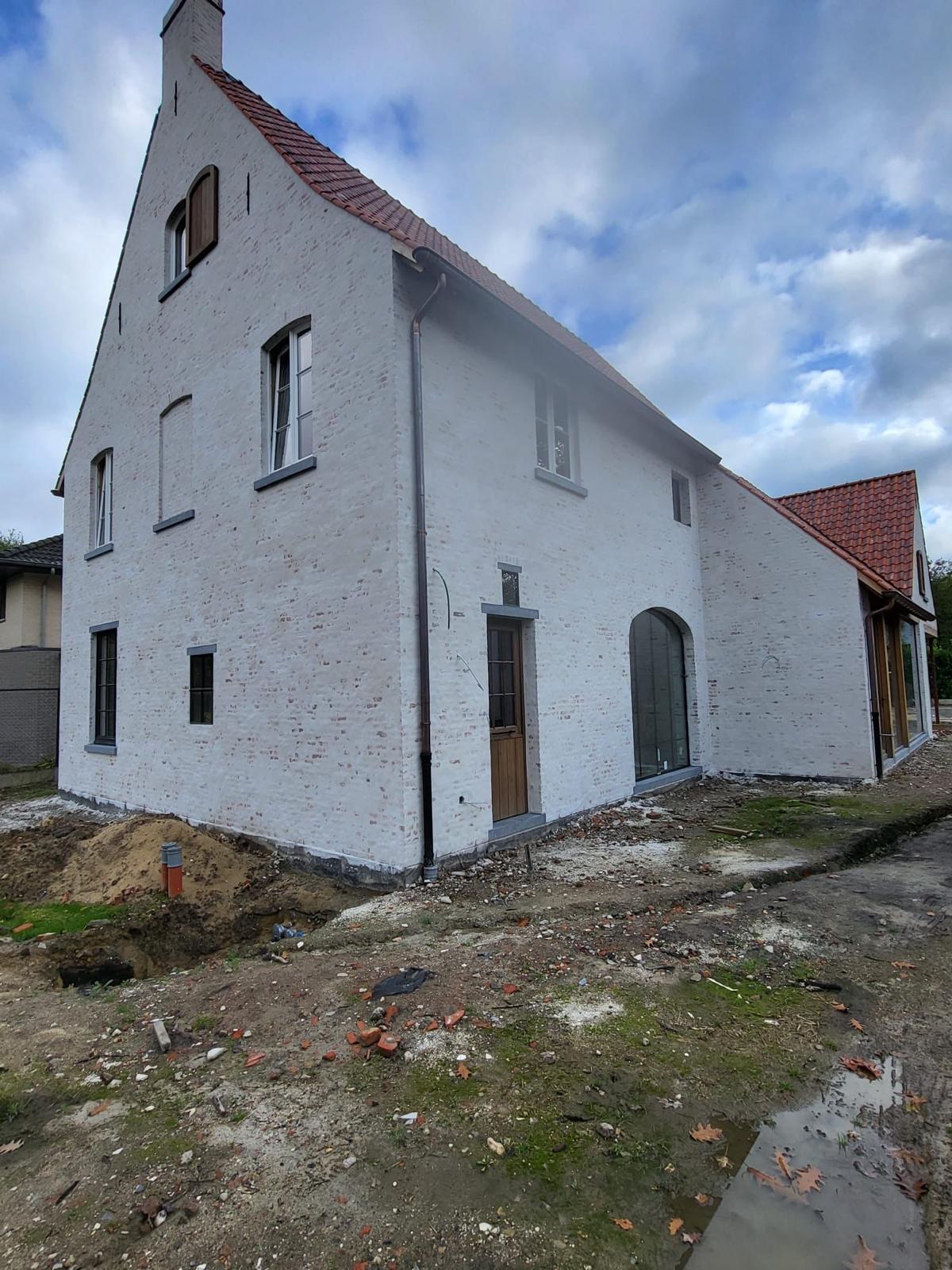 Zijgevel van landelijke nieuwbouwwoning in gekaleide baksteen met boogpartij
