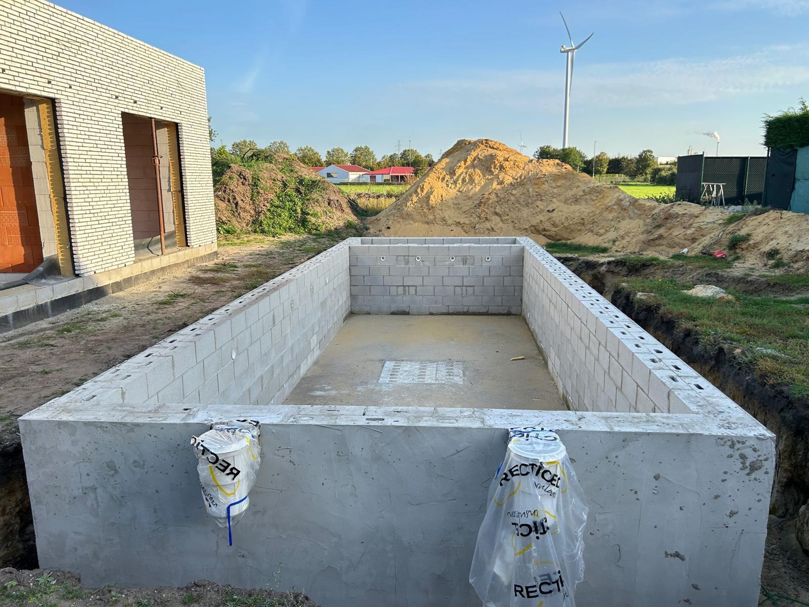 Betonnen en gemetselde zwembadconstructie op werf met isolatie en doorvoeren