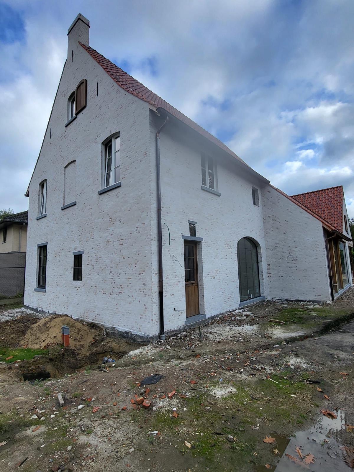 Landelijke woning met witgekaleide gevel, houten deur en glazen boogpartij