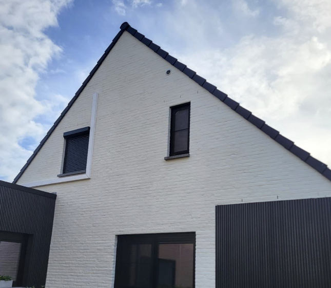 Witgekaleide baksteengevel met zwarte dakpannen en donkere gevelbekleding