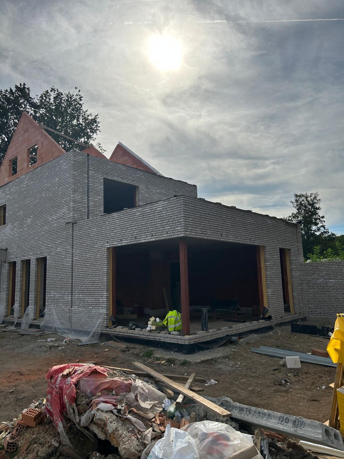 Nieuwbouw met betonnen overkraging en carport in lichtgrijze baksteen